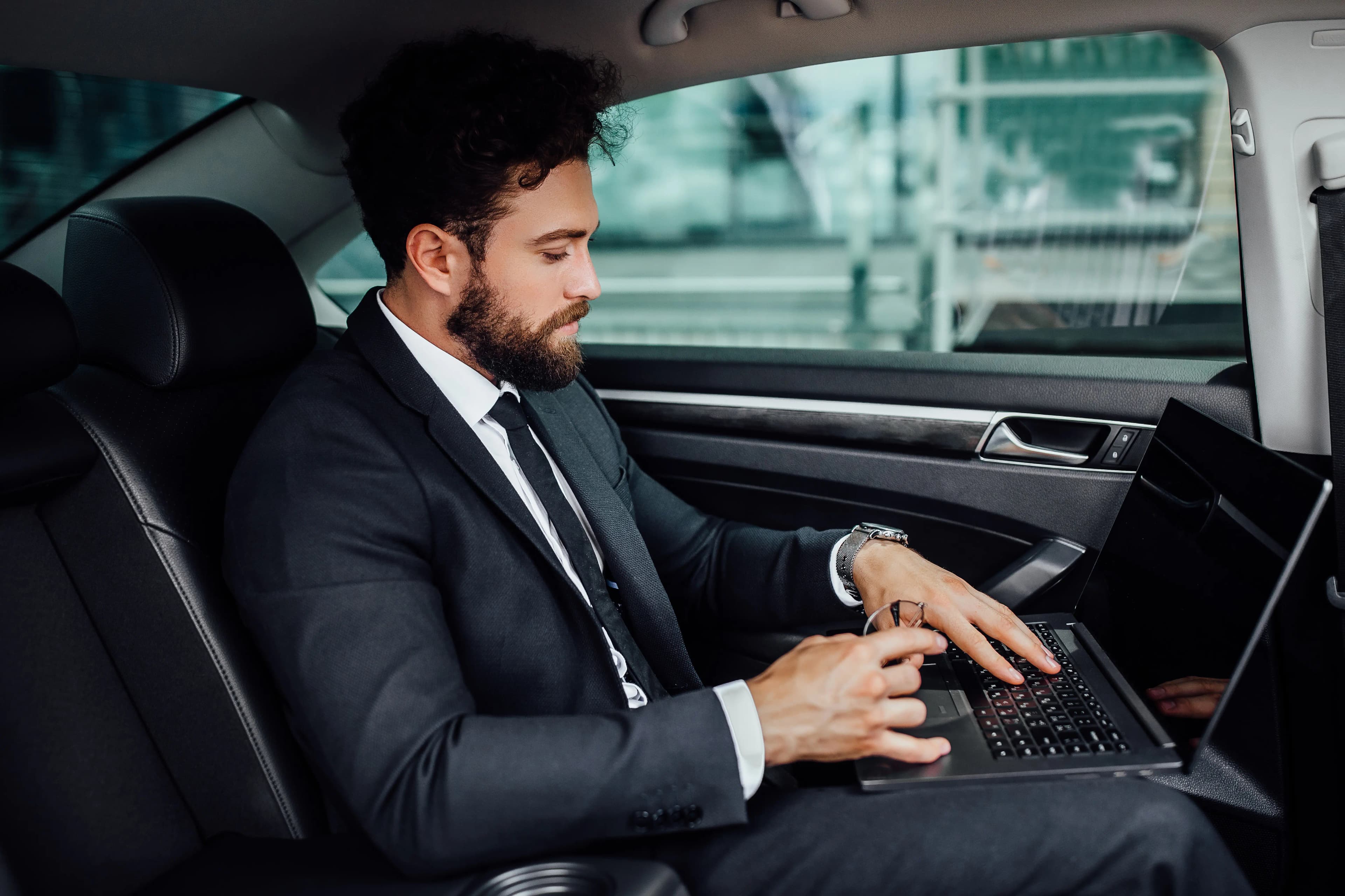 Executive entering a black sedan outside an office tower