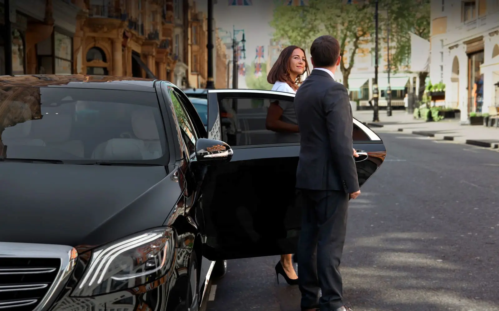 Chauffeur standing beside a luxury sedan